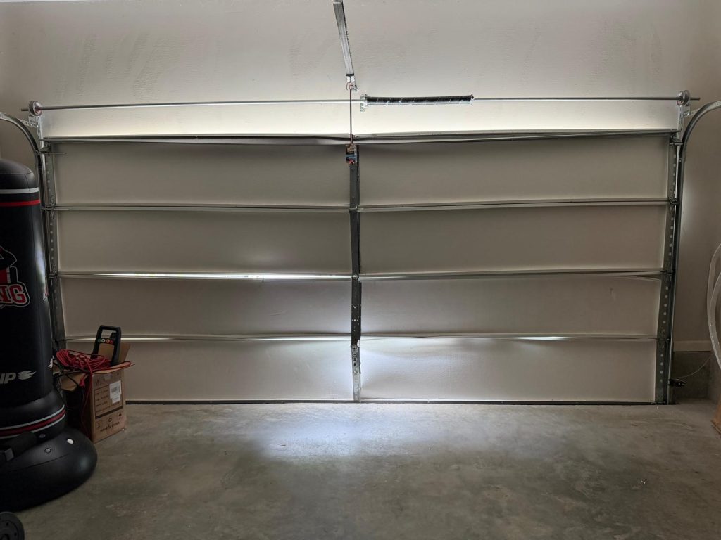 Inside view of a damaged white garage door with a punching bag nearby.