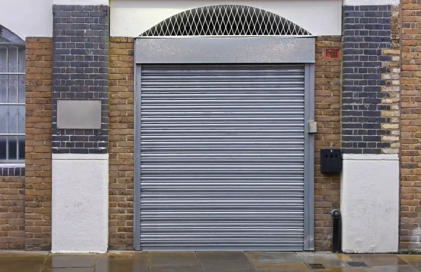 Closed metal roller shutter door on a brick building